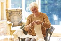 Senior woman knitting in living room — Stock Photo