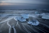 Larga exposición de hielo en la playa fría del océano tormentoso, Jokulsarlon, Islandia - foto de stock