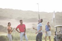 Freunde beobachten Mann, wie er Golfschläger auf Nase balanciert — Stockfoto