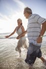 Coppia più anziana che gioca sulle onde sulla spiaggia — Foto stock
