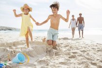 Children kicking down sandcastle on beach — Stock Photo