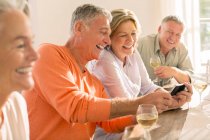 Senioren trinken Wein und schauen aufs Handy — Stockfoto