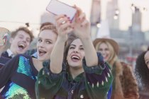 Young women laughing and taking selfie at rooftop party — Stock Photo