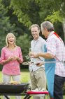 Happy family standing at barbecue in backyard — Stock Photo