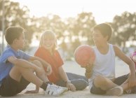 Діти сидять з футбольним м'ячем на відкритому повітрі — стокове фото