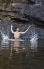 Uomo schizzi in piscina contro roccia — Foto stock