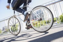 Empresário de seção baixa em terno andar de bicicleta na calçada urbana ensolarada — Fotografia de Stock