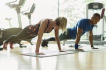 Man and woman doing planks at gym — Stock Photo