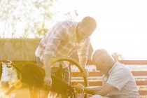 Отец и взрослый сын чинят велосипед — стоковое фото