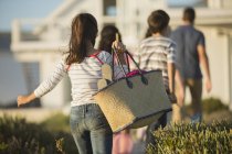 Menina com saco de praia seguinte família — Fotografia de Stock