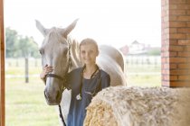 Retrato veterinario sonriente con caballo en granero - foto de stock