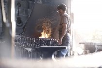 Blacksmith at fire in forge — Stock Photo