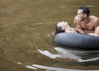 Casal jogando em tubo interno no lago — Fotografia de Stock