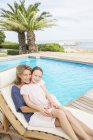 Grandmother and granddaughter relaxing at poolside — Stock Photo