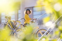 Усміхнена жінка з велосипедом у місті — стокове фото