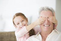 Chica cubriendo abuelos ojos - foto de stock