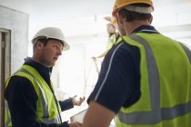 Construction worker and engineer with digital tablet talking at construction site — Stock Photo