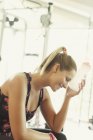 Müde Frau kühlt im Fitnessstudio mit Wasserflasche die Stirn — Stockfoto