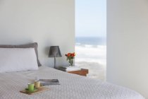 Поднос с чашками эспрессо на кровати в спальне с видом на океан — стоковое фото