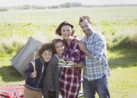 Ritratto famiglia sorridente con hamburger alla brace al campeggio soleggiato — Foto stock