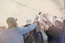 Enthusiastic young adult friends toasting cocktails at rooftop party — Stock Photo