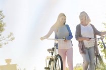 Madre e hija adulta caminando bicicletas - foto de stock