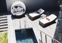 Cadeiras de estar no deck de madeira pela piscina moderna — Fotografia de Stock