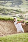 Woman swinging from sand trap on golf course — Stock Photo
