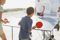 Семья играет в настольный теннис вместе на открытом воздухе — стоковое фото