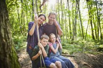 Portrait smiling family at rope swing in woods — Stock Photo