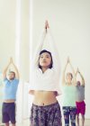 Mujer seria con los brazos levantados en clase de yoga - foto de stock