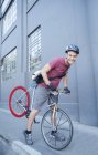 Portrait smiling bicycle messenger with helmet leaning forward on urban sidewalk — Stock Photo