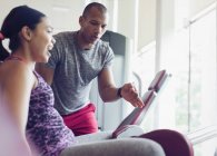 Personal trainer guiding woman on exercise equipment at gym — Stock Photo