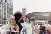 Friends with map riding double-decker bus, London, United Kingdom — Stock Photo