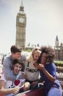 Enthusiastic friends riding double-decker bus below Big Ben clocktower, London, United Kingdom — Stock Photo