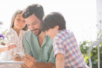 Father and children using cell phone outdoors — Stock Photo