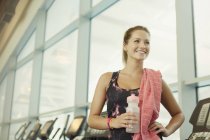 Усміхнена жінка відпочиває і п'є воду в спортзалі — стокове фото