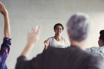 Teacher calling on students with hands raised in adult education classroom — Stock Photo