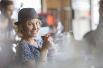 Retrato sorridente mulher de chapéu bebendo café expresso no café — Fotografia de Stock