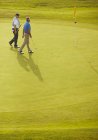 Seniores caminhando no campo de golfe — Fotografia de Stock