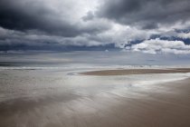 Хмари над пляжем при низькому припливі — стокове фото