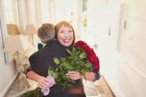 Mulheres felizes recebendo buquê de rosa e abraçando o marido — Fotografia de Stock