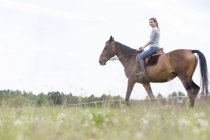 Woman horseback riding in rural field — Stock Photo