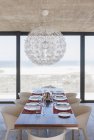 Table dressée dans la salle à manger moderne donnant sur l'océan — Photo de stock