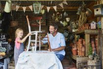 Father and daughter painting chair in workshop — Stock Photo