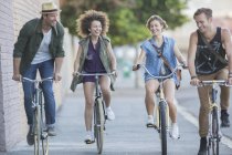 Friends riding bicycles on urban sidewalk — Stock Photo