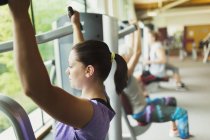 Mujer enfocada usando equipo de ejercicio en el gimnasio - foto de stock