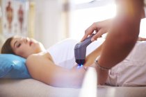Fisioterapeuta usando sonda de ultrasonido en brazo de mujer - foto de stock