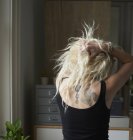 Junge Frau mit Händen im Haar, die Tätowierungen im Rücken enthüllt — Stockfoto