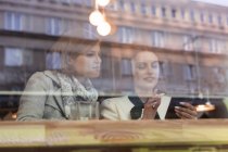 Бізнес-леді використовують мобільний телефон у вікні кафе — стокове фото